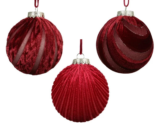 Three oxblood red velvet-finished Christmas baubles in assorted ribbed, swirled, and paneled designs with gold caps and thread hangers.