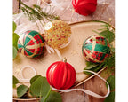 Decorative Christmas ornaments on a wooden surface with greenery