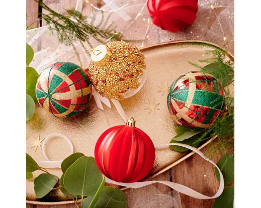 Decorative Christmas ornaments on a wooden surface with greenery