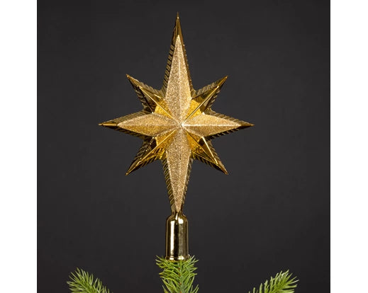 Gold star-shaped Christmas tree topper on a dark background