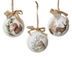 Three Christmas ornaments with nature-themed designs on a white background