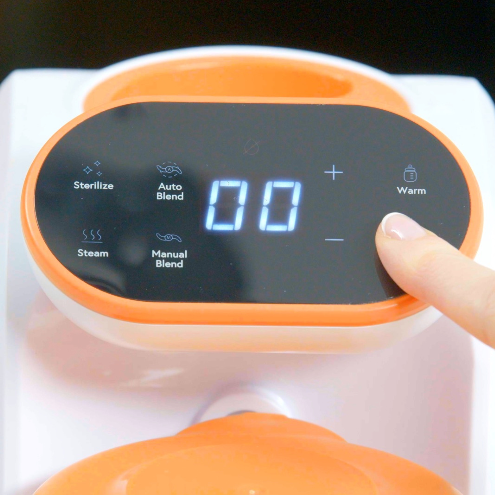 Digital display on a kitchen appliance with buttons and a finger pressing one.