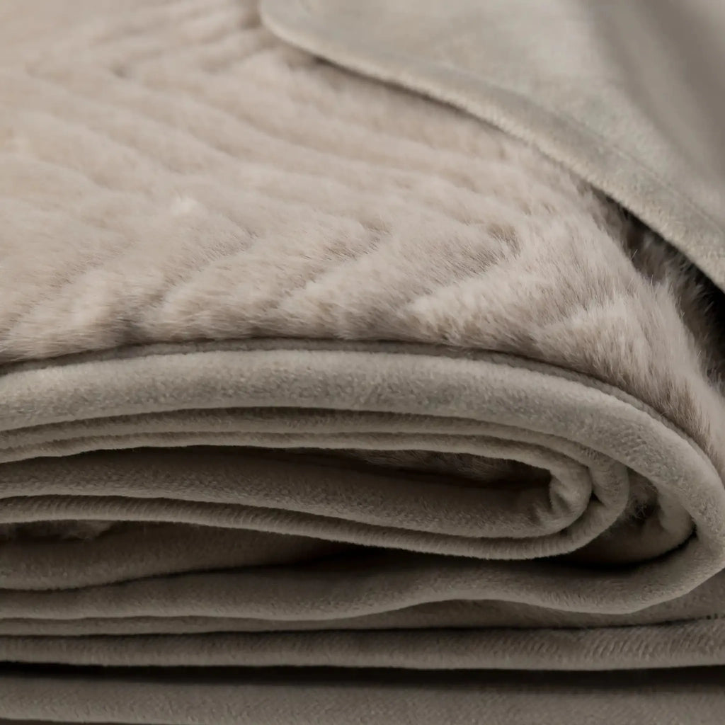 A close-up of a folded pEllis Throw in Mink - full view showing its soft texture and stitched chevron pattern.