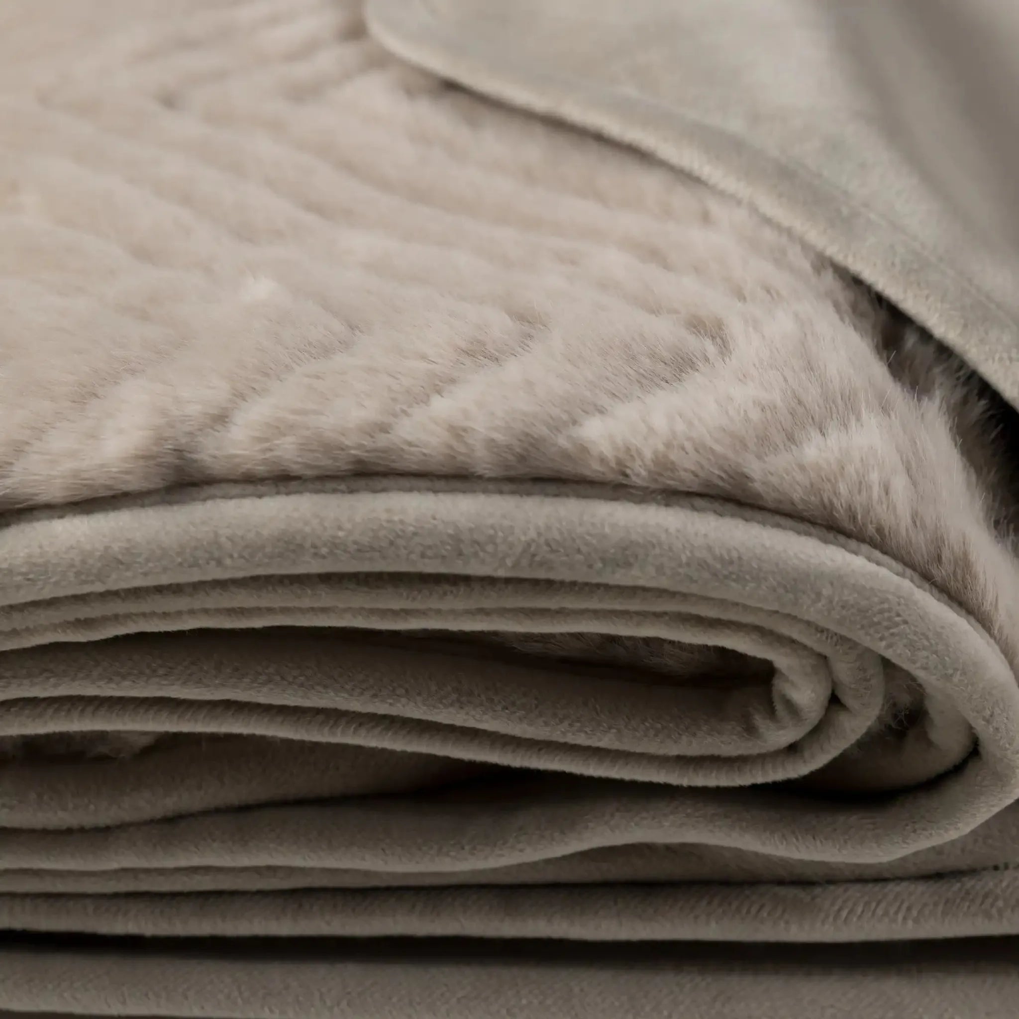 A close-up of a folded pEllis Throw in Mink - full view showing its soft texture and stitched chevron pattern.