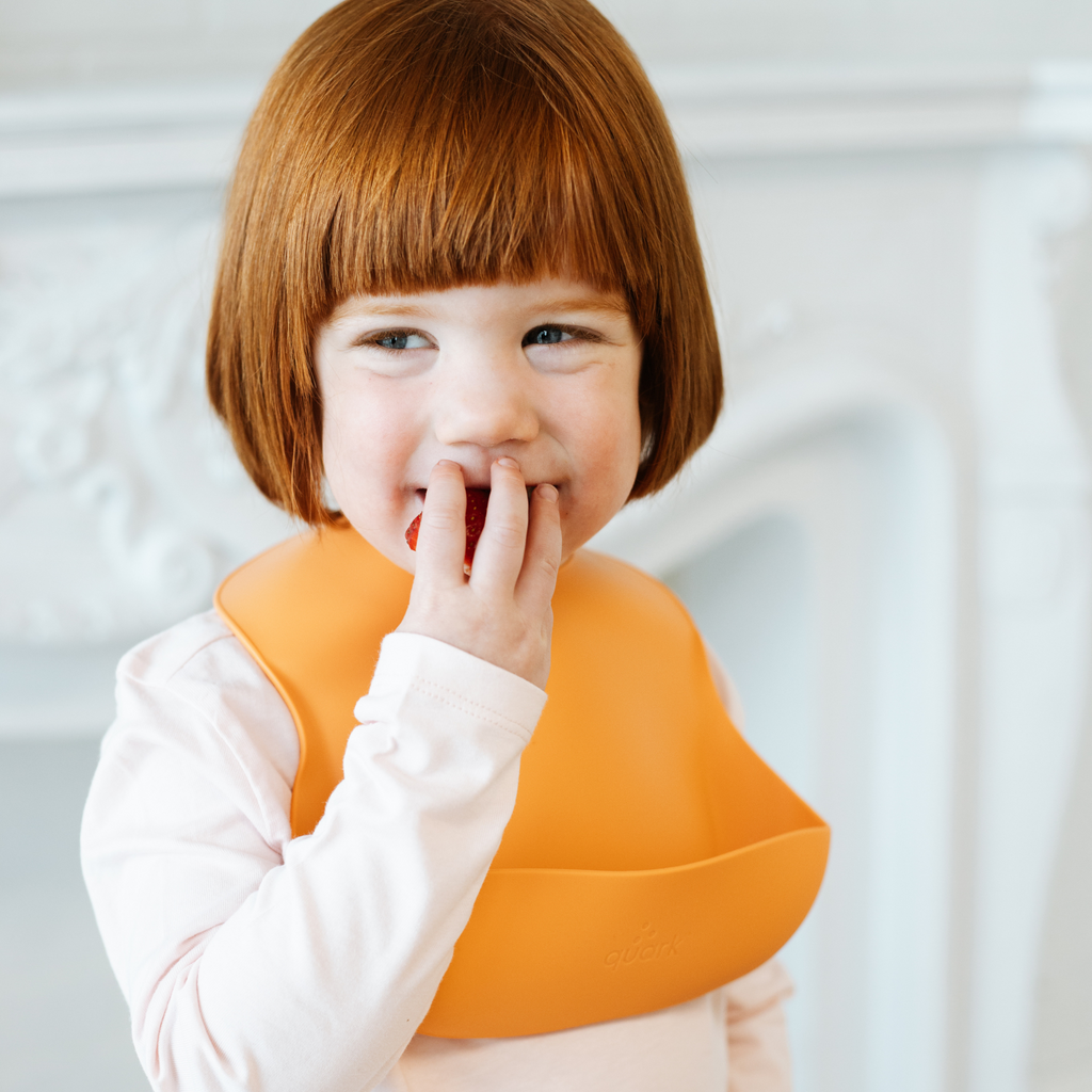 Child wearing an orange bib with a blurred background