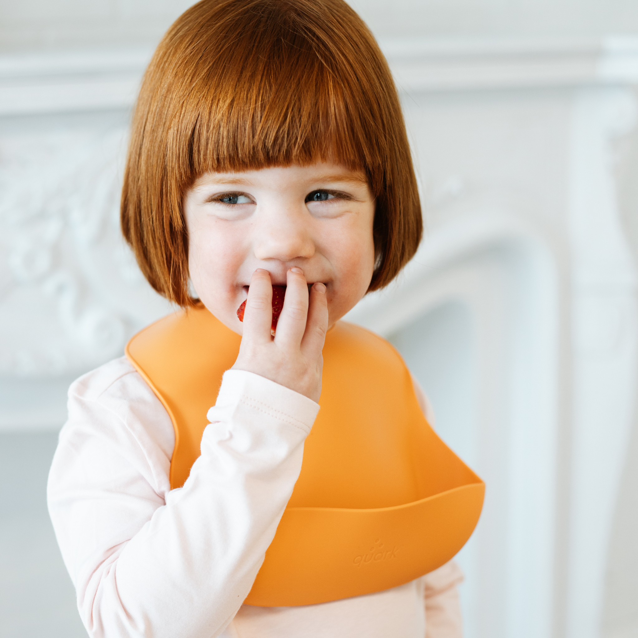 Child wearing an orange bib with a blurred background