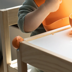 Child playing with wooden toys at a table and Quark Foxii protecting the corners of the table 
