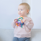 Child holding a colorful teething ring against a light background