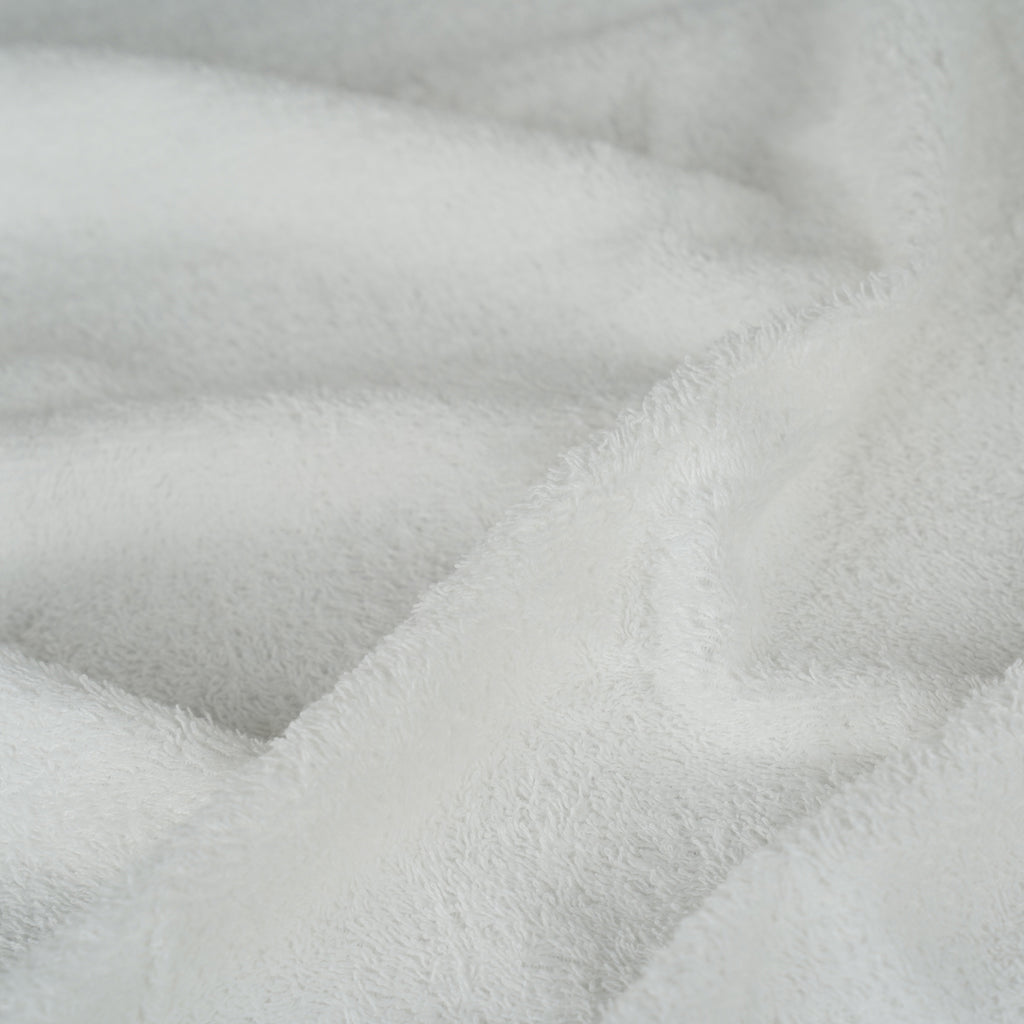 A close-up of soft white plush fabric with a textured, terry-like surface and gentle folds.