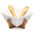 A white ceramic salad bowl set with a wooden stand and including wooden salad utensils.
