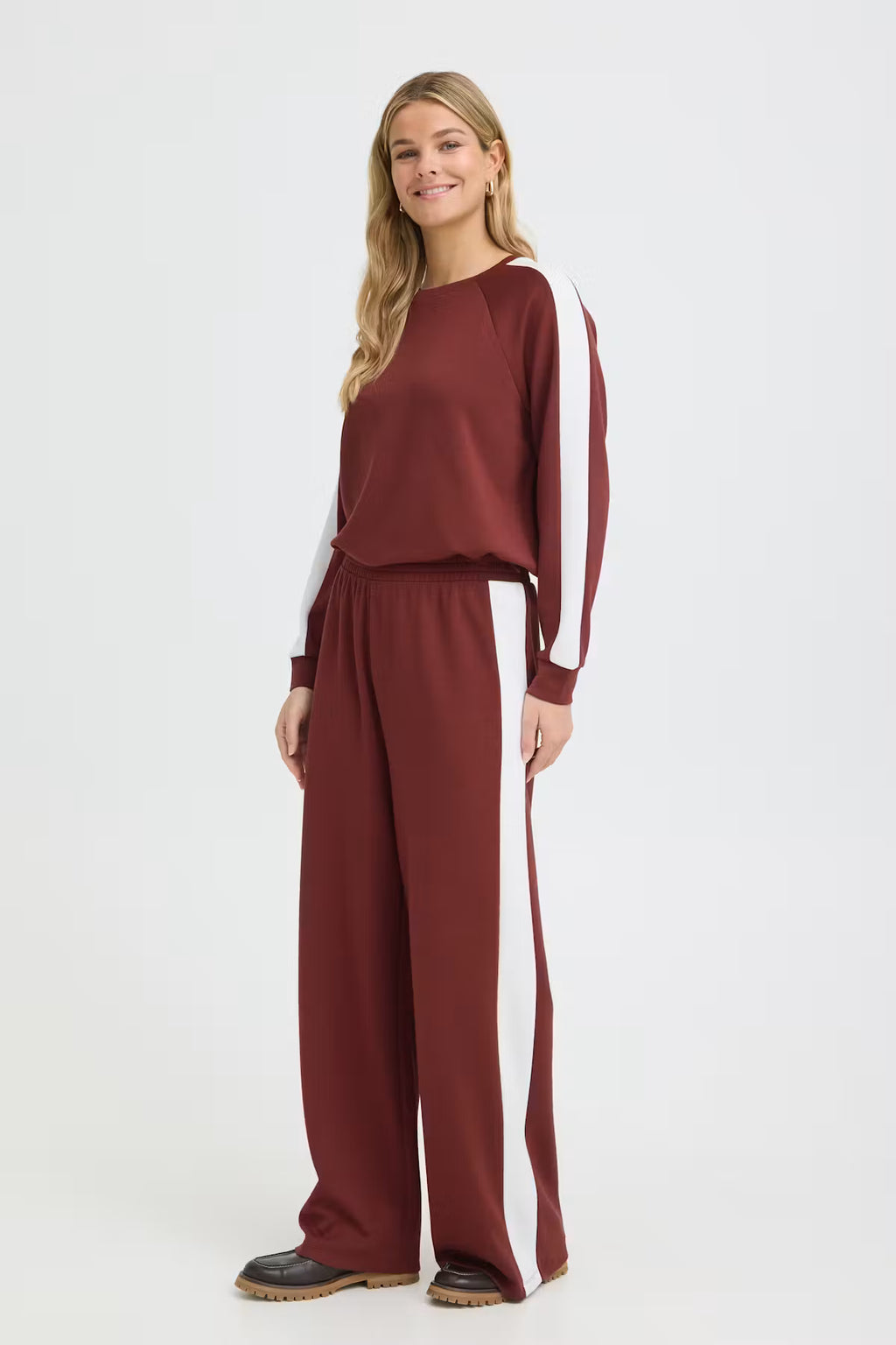 Woman wearing a maroon outfit with white stripes on a white background