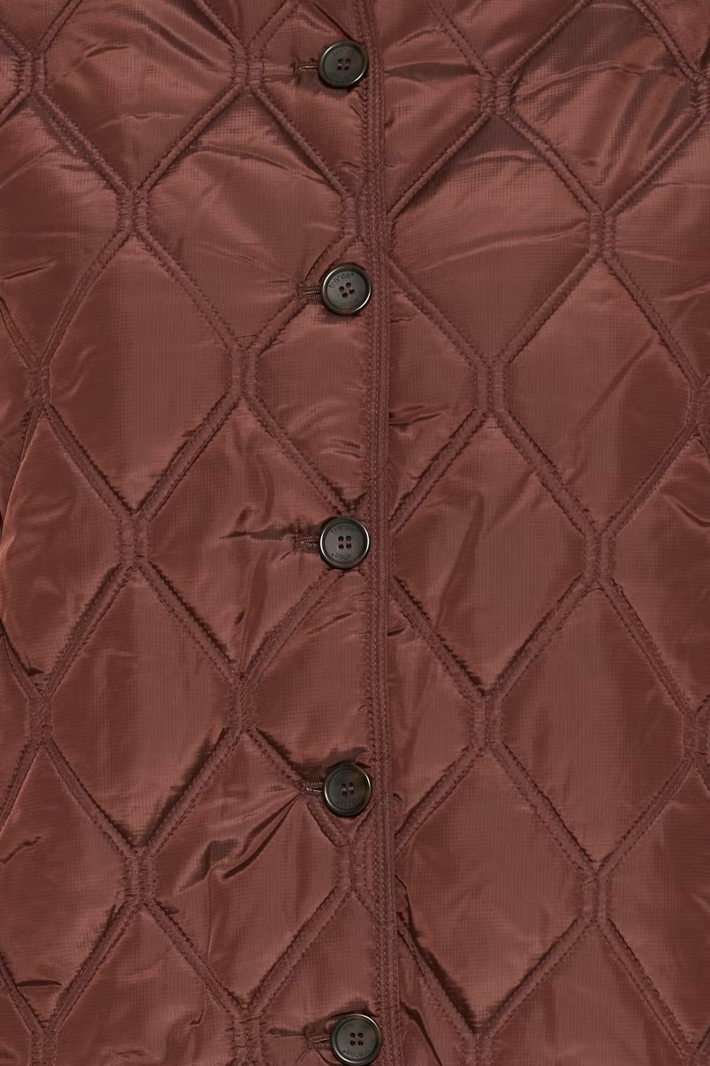 Close-up of a FRAGATE Outerwear in Rum Raisin/Red, featuring a diamond quilting pattern and a vertical row of dark buttons down the center front.