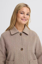A woman wearing FREVILLA Outerwear in Rain-Drum Mix/Brown coat with a collar and brown buttons, photographed against a light gray studio background.