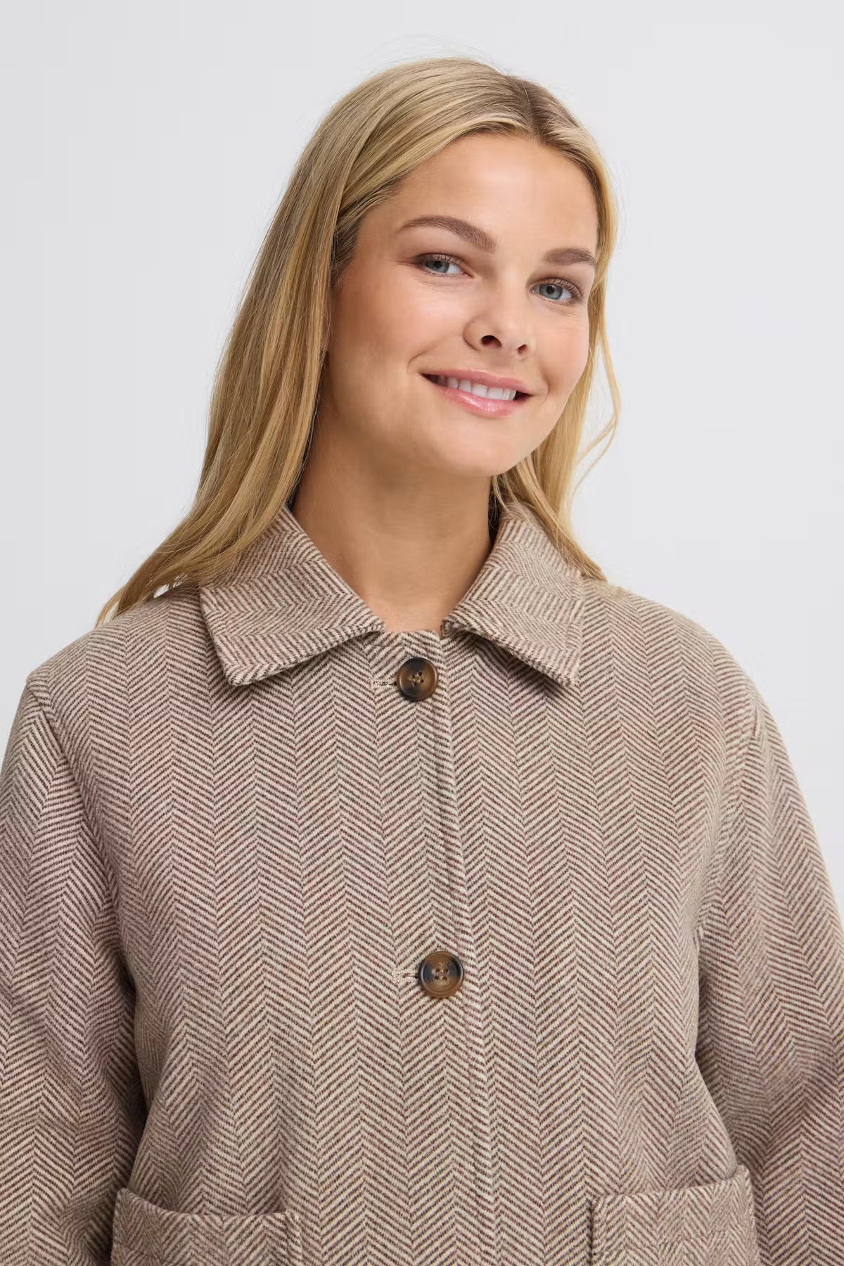 A woman wearing FREVILLA Outerwear in Rain-Drum Mix/Brown coat with a collar and brown buttons, photographed against a light gray studio background.