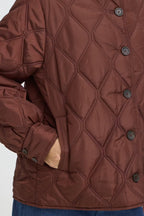 Close-up of a FRAGATE Outerwear in Rum Raisin/Red with dark buttons, showing part of a person's hand in a pocket and blue jeans at the bottom.