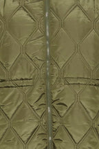 Close-up of a quilted jacket FRAGATE Outerwear in Grape Leaf/Green with a central zipper and stitched diamond pattern.