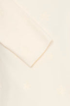 A close-up of a Whisper White pullover with a subtle tonal embroidered pattern .