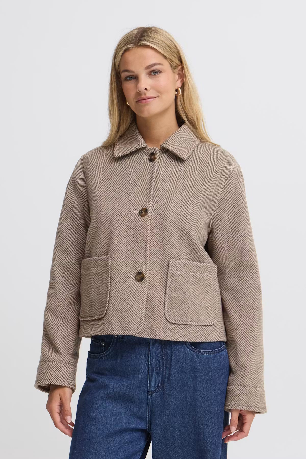 A woman modeling a cropped FREVILLA Outerwear in Rain-Drum Mix/Brown, three front buttons, and two large front patch pockets, paired with blue jeans against a light gray studio background.