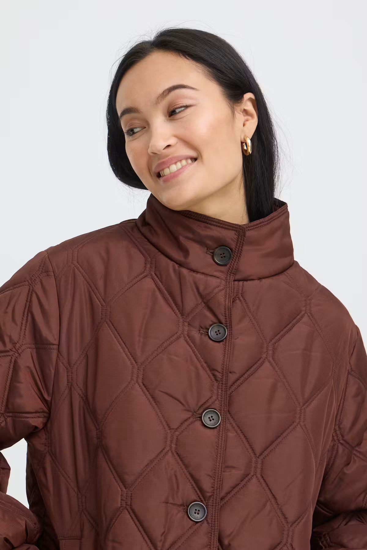 A woman wearing a FRAGATE Outerwear in Rum Raisin/Red with a high stand-up collar and dark buttons, shown from the chest up against a light gray studio background.