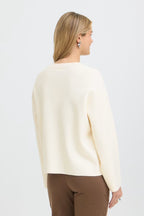 A woman shown from the back wearing Whisper White pullover and brown trousers against a plain white studio background.