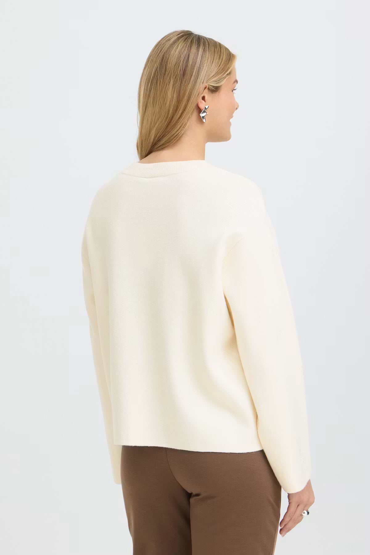 A woman shown from the back wearing Whisper White pullover and brown trousers against a plain white studio background.