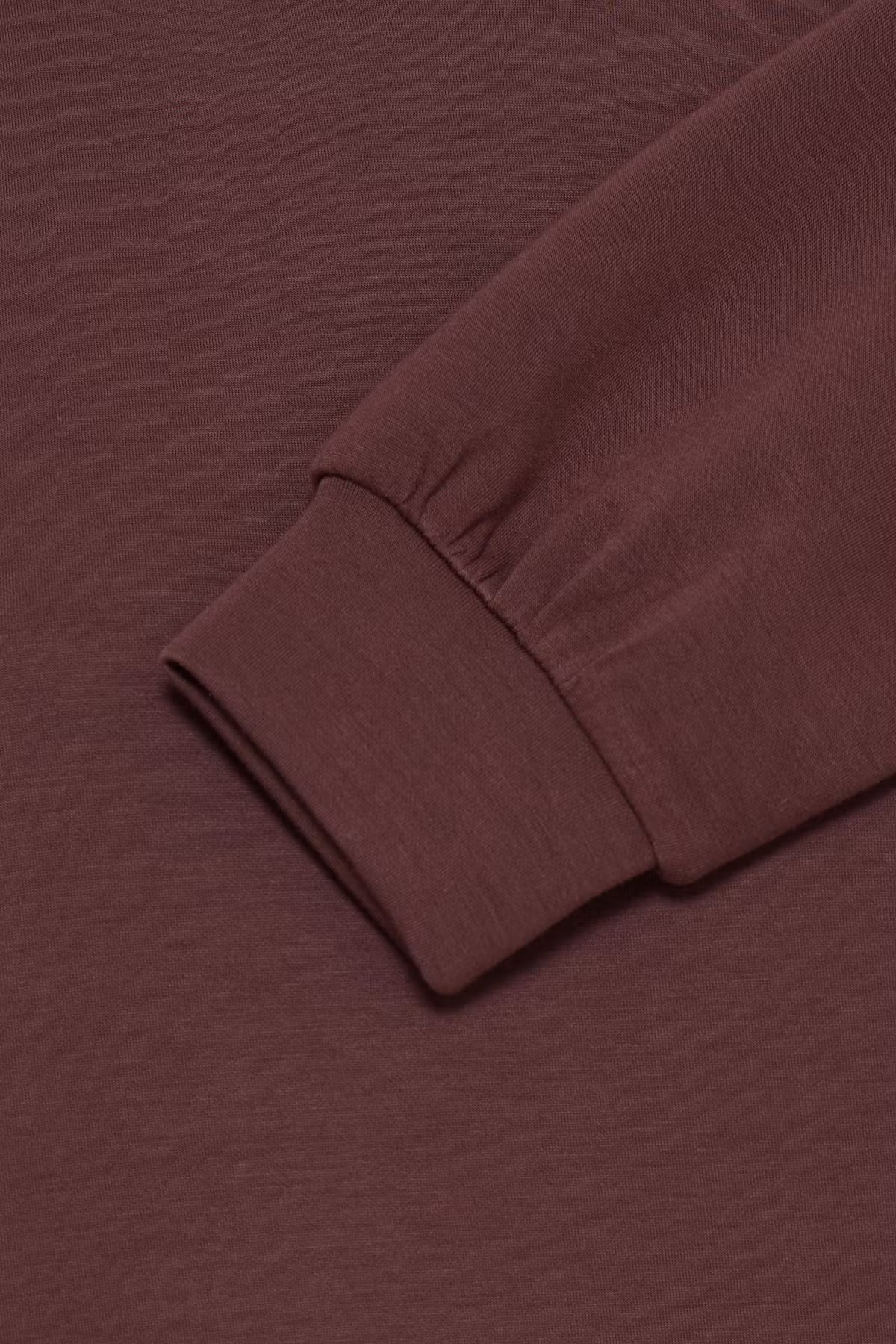 Close-up of a ribbed long-sleeve cuff in a FRAURORA PU 7 Sweatshirt in Rum Raisin/Red , showing the texture and fold of the sleeve against a matching background.