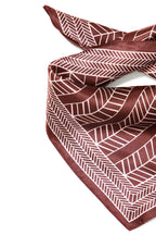 A Rum Raisin scarf with a white geometric herringbone pattern, styled in a loose knot on a plain white background.