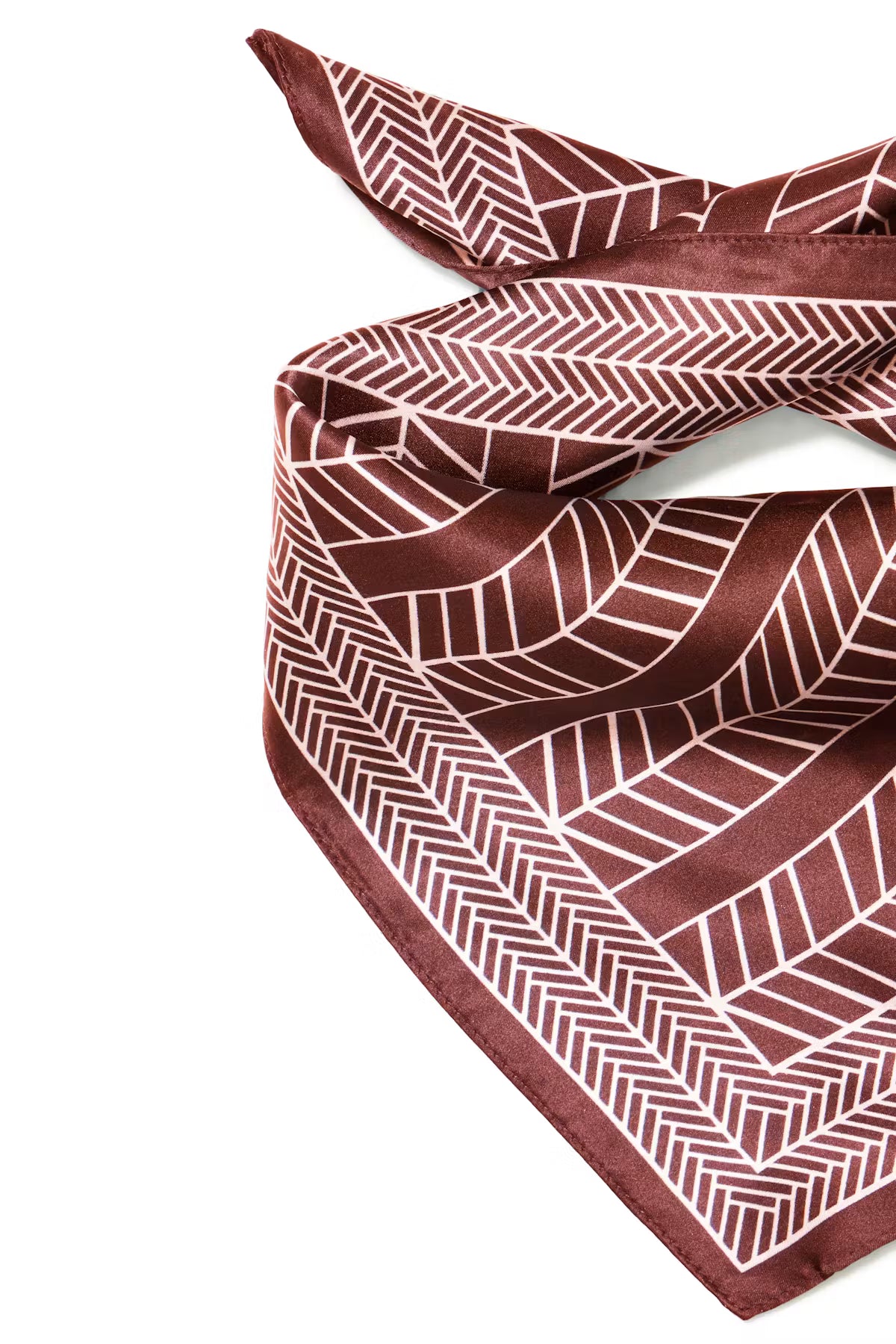 A Rum Raisin scarf with a white geometric herringbone pattern, styled in a loose knot on a plain white background.