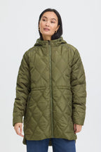 A woman wearing FRAGATE Outerwear in Grape Leaf/Green with a diamond-stitched pattern, shown against a plain light gray studio background.