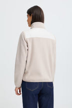A woman shown from the back wearing FRFLEA Outerwear in String/Nature paired with dark blue jeans against a light gray studio background.