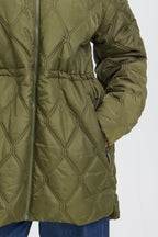 Close-up of an FRAGATE Outerwear in Grape Leaf/Green quilted puffer jacket with a diamond stitching pattern, a drawstring waist, and a front zipper, worn by a model with blue jeans visible at the bottom.