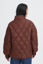 A person shown from the back wearing a FRAGATE Outerwear in Rum Raisin/Red with a diamond pattern, paired with blue jeans, against a plain light gray background.