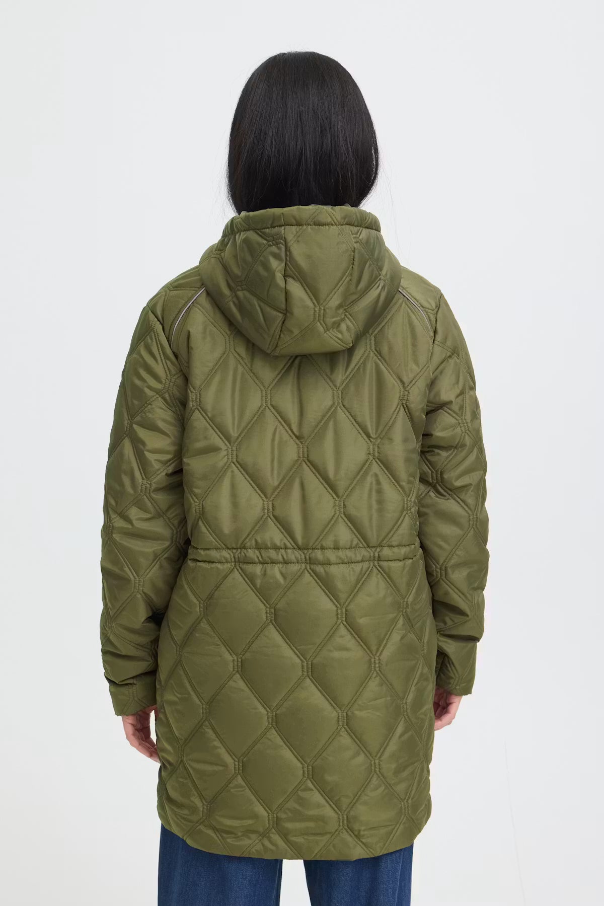 A person shown from the back wearing a quilted hooded jacket in FRAGATE Outerwear in Grape Leaf/Green, paired with blue jeans, against a plain light gray studio background.