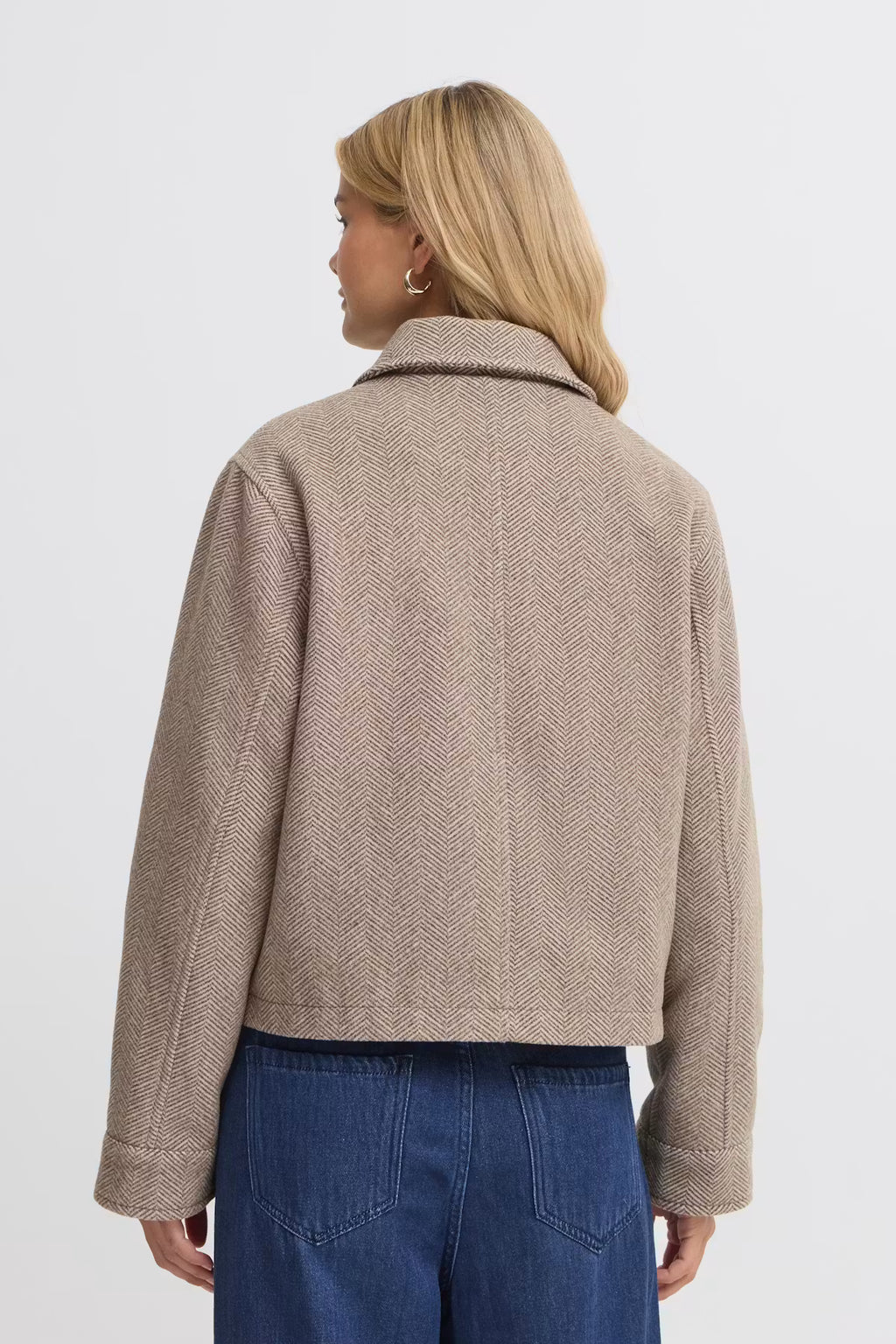 A woman shown from the back wearing a cropped FREVILLA Outerwear in Rain-Drum Mix/Brown and blue jeans against a plain light gray studio background.