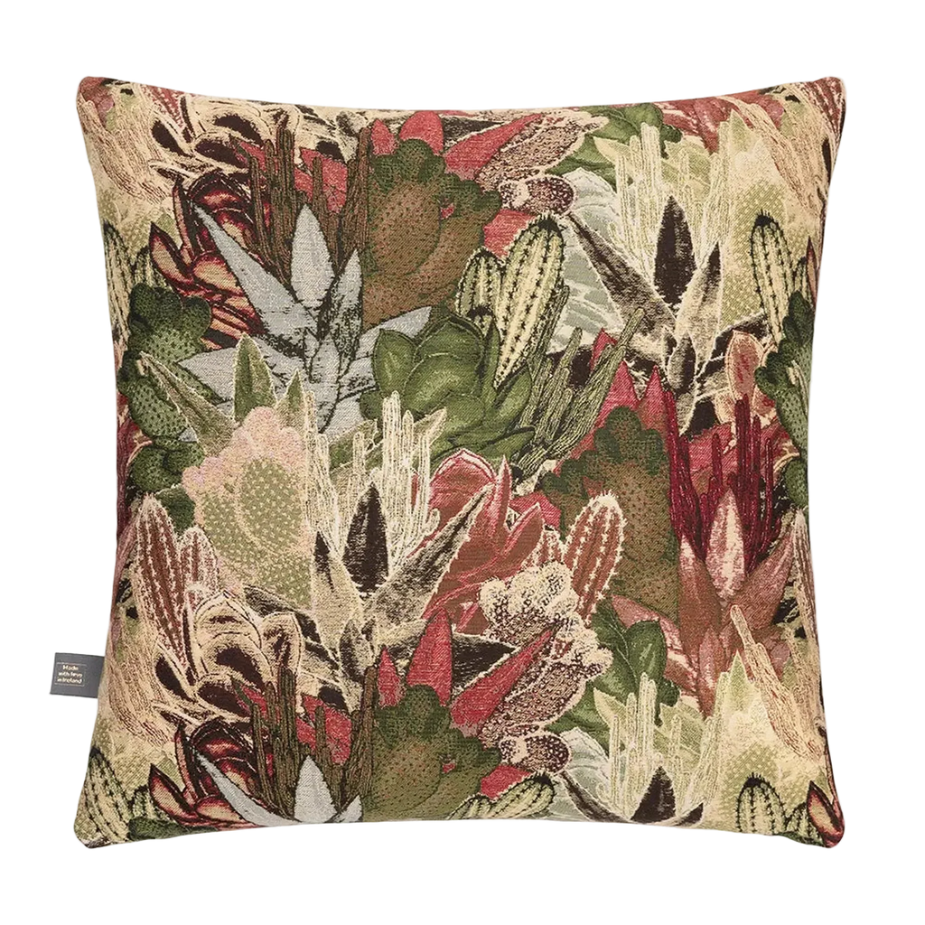A square decorative tMerida Cushion in Green featuring a detailed woven botanical pattern of cacti, succulents, and leaves in shades of green, beige, rust red, and brown, shown against a plain white background.