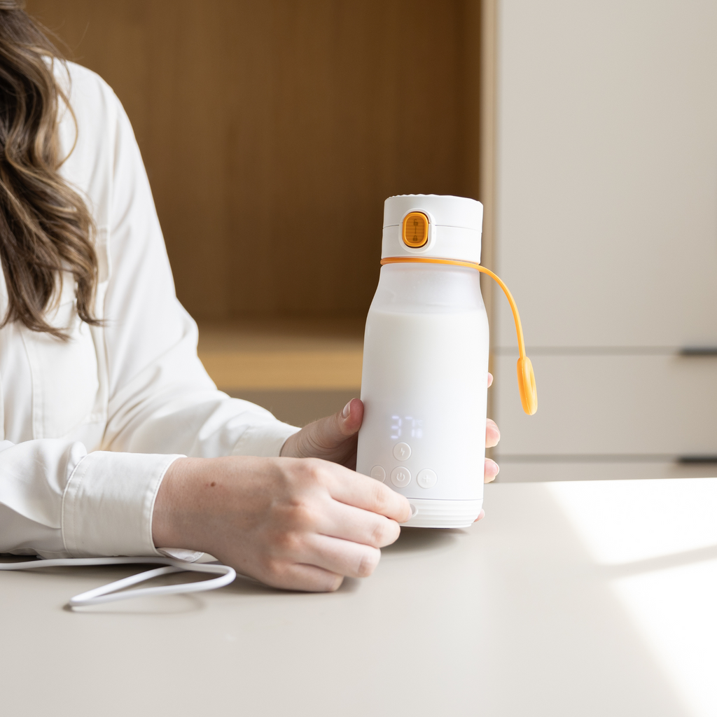 Person holding a white water bottle with a yellow strap on a table.