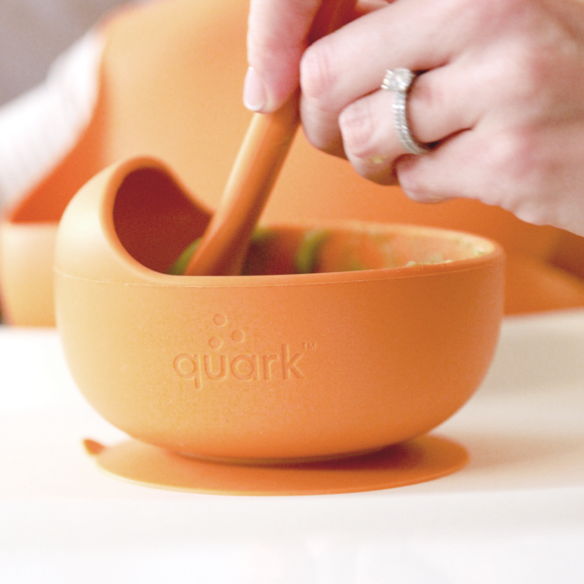 Orange 'quark' bowl with a wooden spoon on a white background