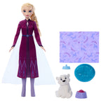 Frozen doll with accessories including a purple outfit, white bear, blue dish, and patterned fabric on a white background.