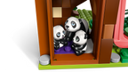 LEGO panda family inside a wooden cabin on a white background