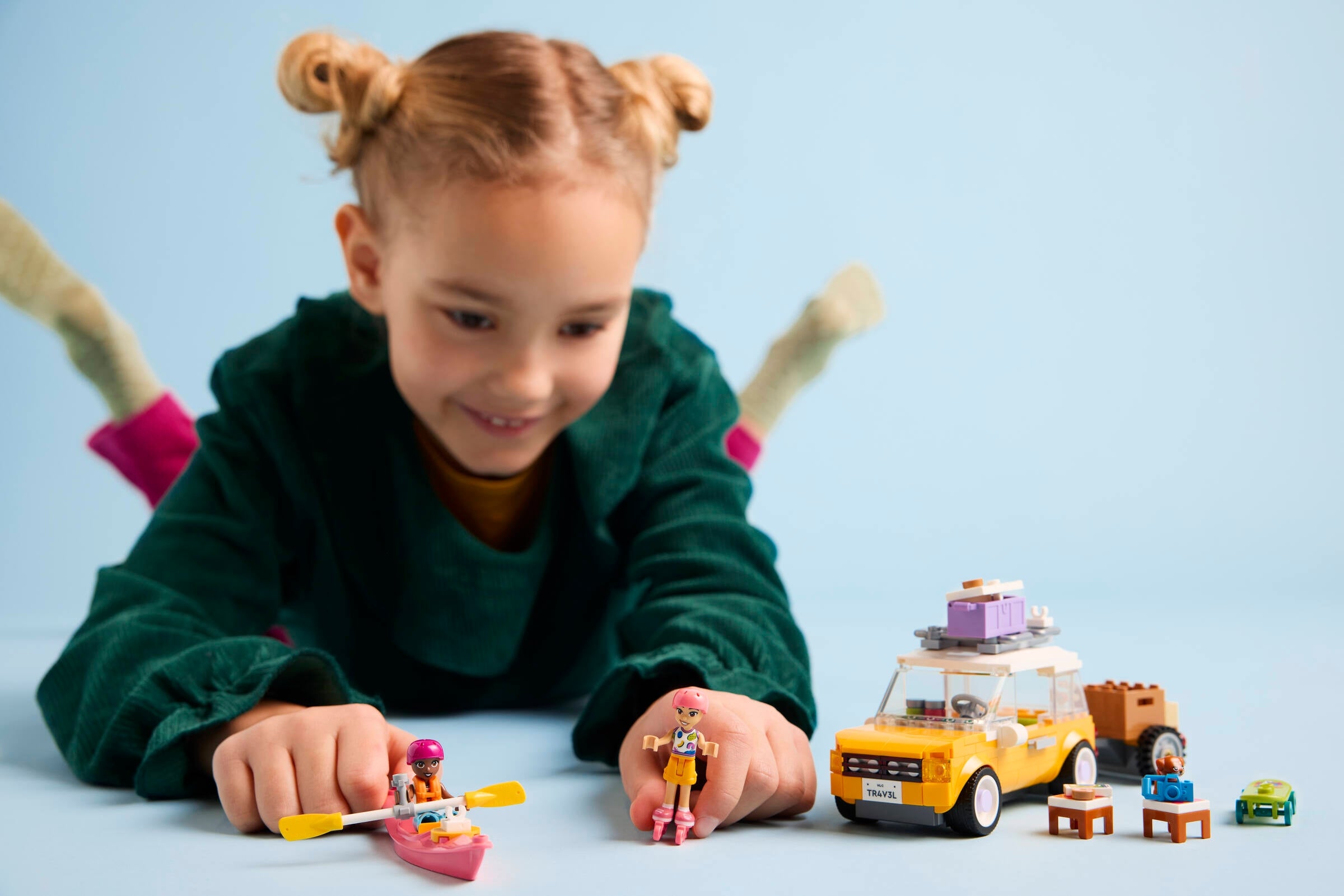 Child playing with toy cars and figures on a light blue background