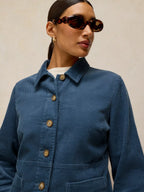 Woman wearing a blue corduroy jacket with a neutral background