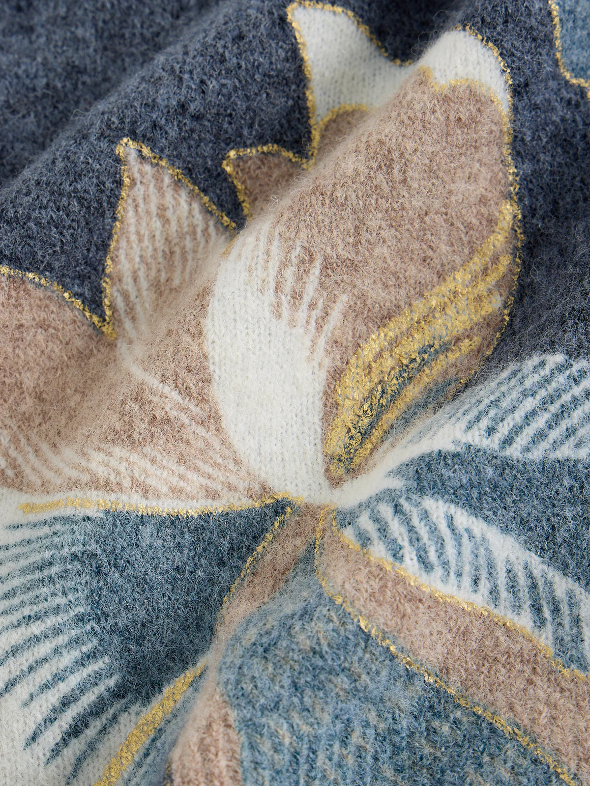 Close-up of a textured fabric with floral pattern in blue, beige, and gold.