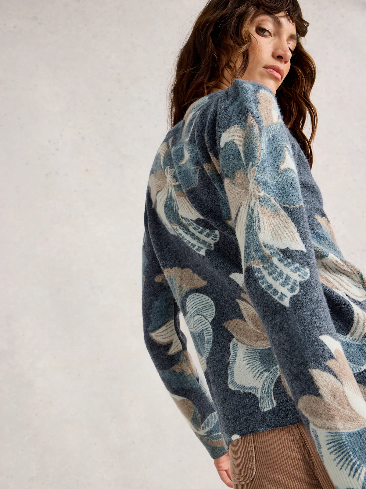 Woman wearing a blue floral patterned sweater against a plain background