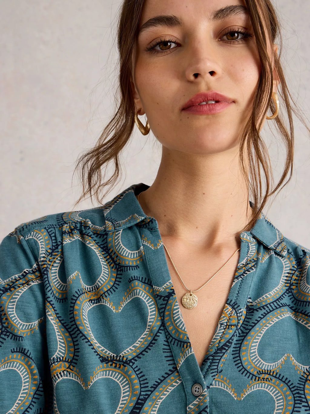 Woman wearing a blue patterned shirt with a neutral background