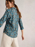 Woman wearing a blue patterned shirt against a plain background