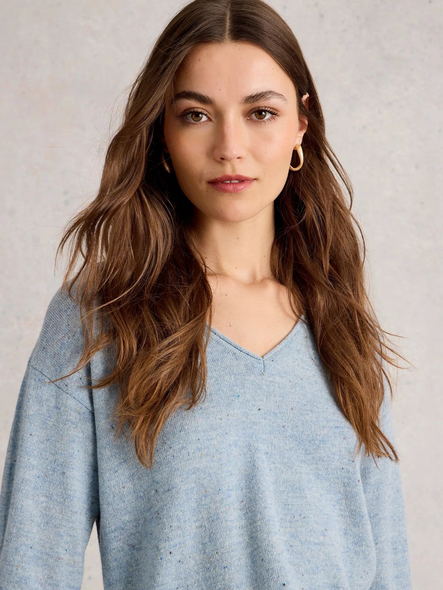 Woman wearing a light blue sweater against a neutral background