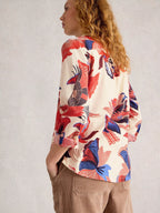 Woman wearing a colorful floral blouse with a plain background