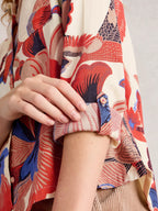 Close-up of a person wearing a colorful patterned garment with a neutral background