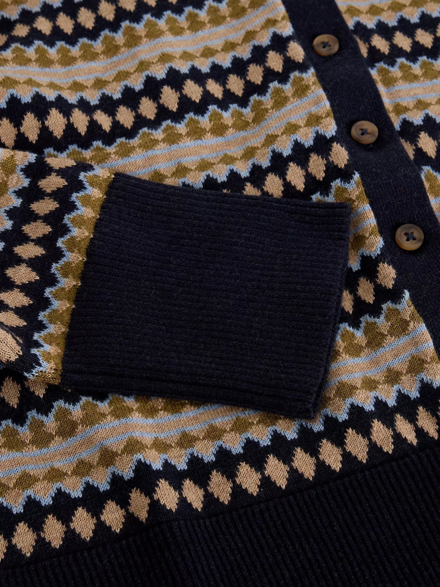 Close-up of a patterned sweater with a dark pocket and buttons.