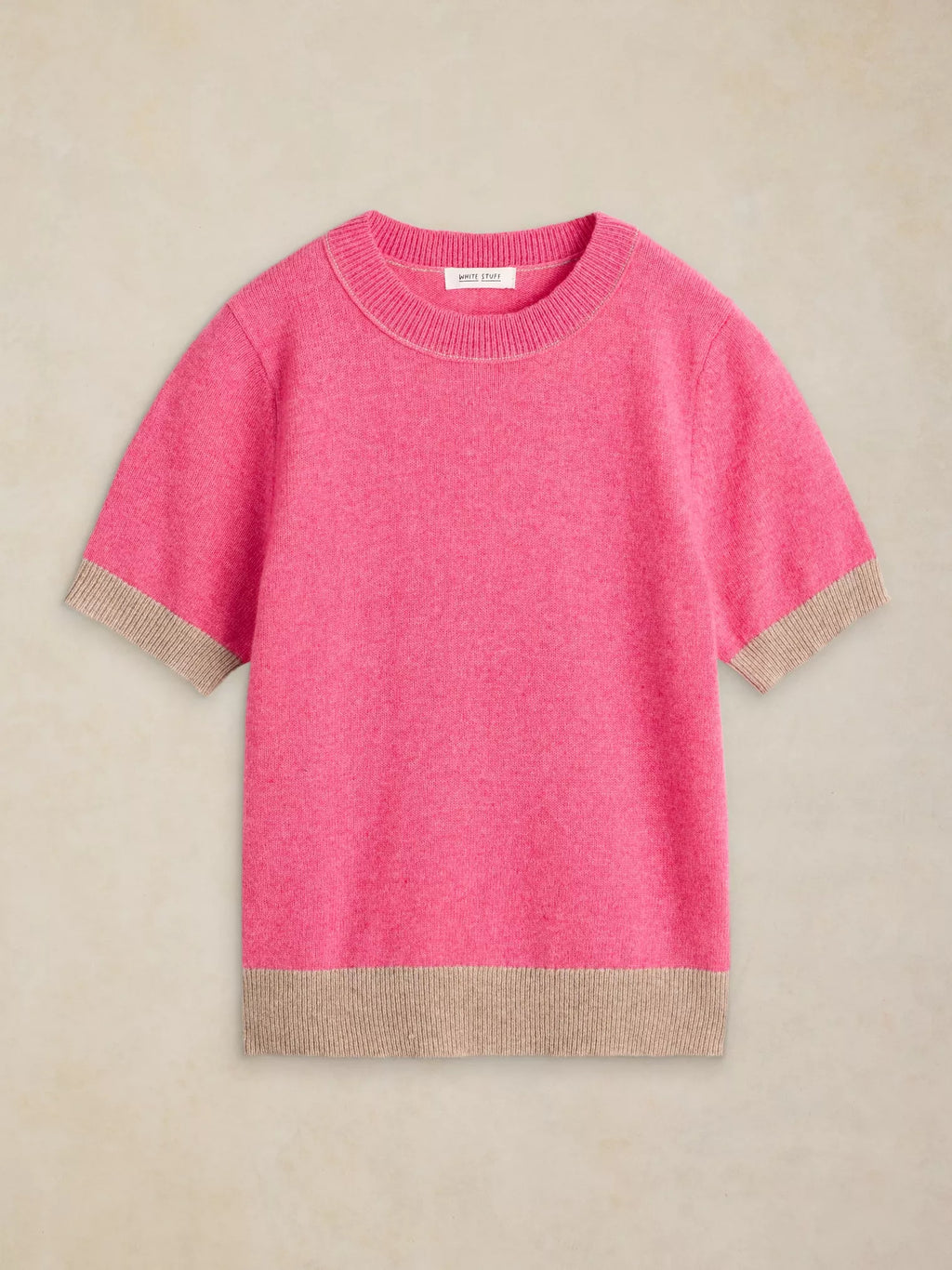 A short-sleeve crewneck knit sweater in bright pink with contrasting beige ribbed trim at the cuffs and hem, displayed flat against a neutral beige background.
